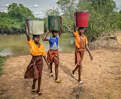 Three girls walking back from a river with water containers
