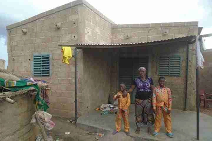 Asseta Zangre with her kids standing outside their house.